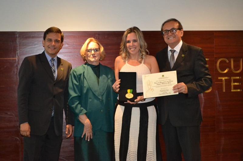 A diretora-geral do IFG - Câmpus Aparecida de Goiânia, professora Ana Lucia Siqueira de Oliveira, ao receber a Medalha em homenagem ao curso de Licenciatura em Dança. Na foto, ela está com o secretário da Casa Civil, Anderson Máximo, a presidente do Conselho Estadual de Cultura, Nancy Ribeiro de Araújo, e o secretário Estadual de Cultura, Edival Lourenço