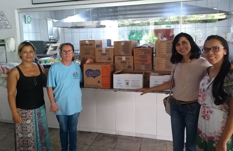 Da esquerda para a direita: Silvia Ferreira de Souza (representante de turma do 2º período do curso Técnico em Modelagem do Vestuário), Irene Rodrigues Pereira (diretora do Abrigo Comendador Walmor), professora Yane Ondina de Almeida (coordenadora do curso Técnico em Modelagem do Vestuário) e professora Joana Cristina Neves de Menezes Faria (coordenadora do Projeto Integrador Educação Socioambiental), no momento da entrega dos produtos adquiridos com a renda do Bazar da Modelagem